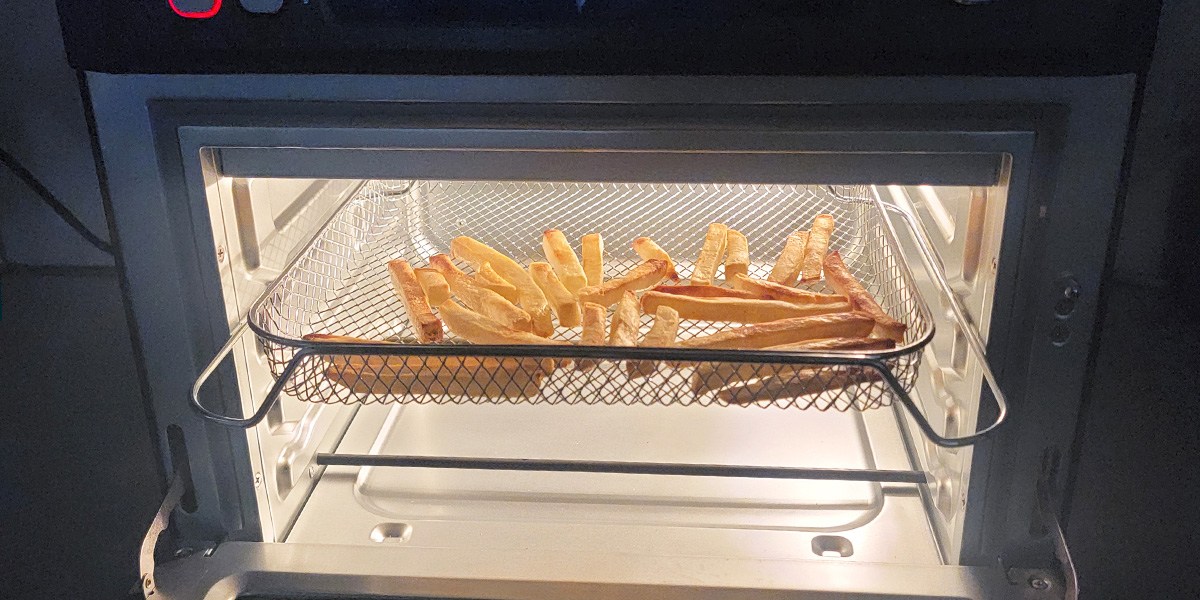 Closeup of fries in basket cooking in Cosori Air Fryer Toaster Oven Closeup of fries in basket cooking in Cosori Air Fryer Toaster Oven