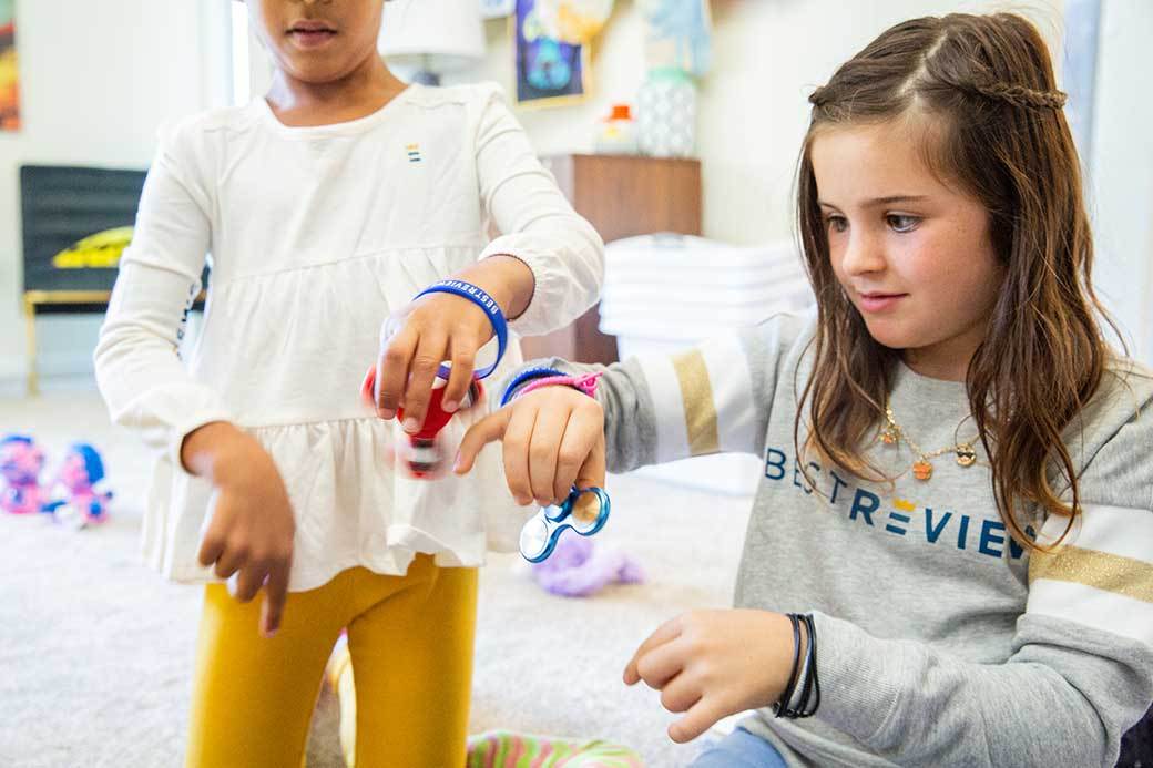 Two children play with fidget spinners
