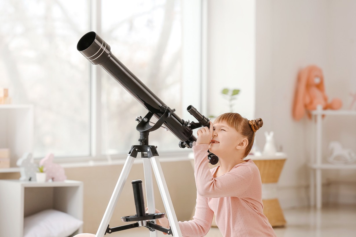 a girl looking through a telescope
